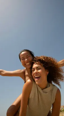 Two friends laughing together at sunset